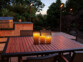 Pack de trois bougies LED jaune blanc chaud posées sur une table de jardin en extérieur